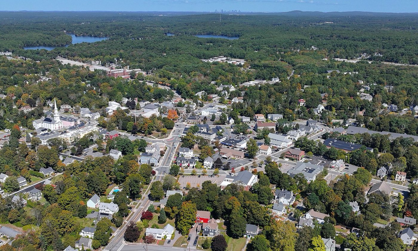 Aerial view of downtown Foxborough, Massachusetts, with the Boston skyline visible in the distance.