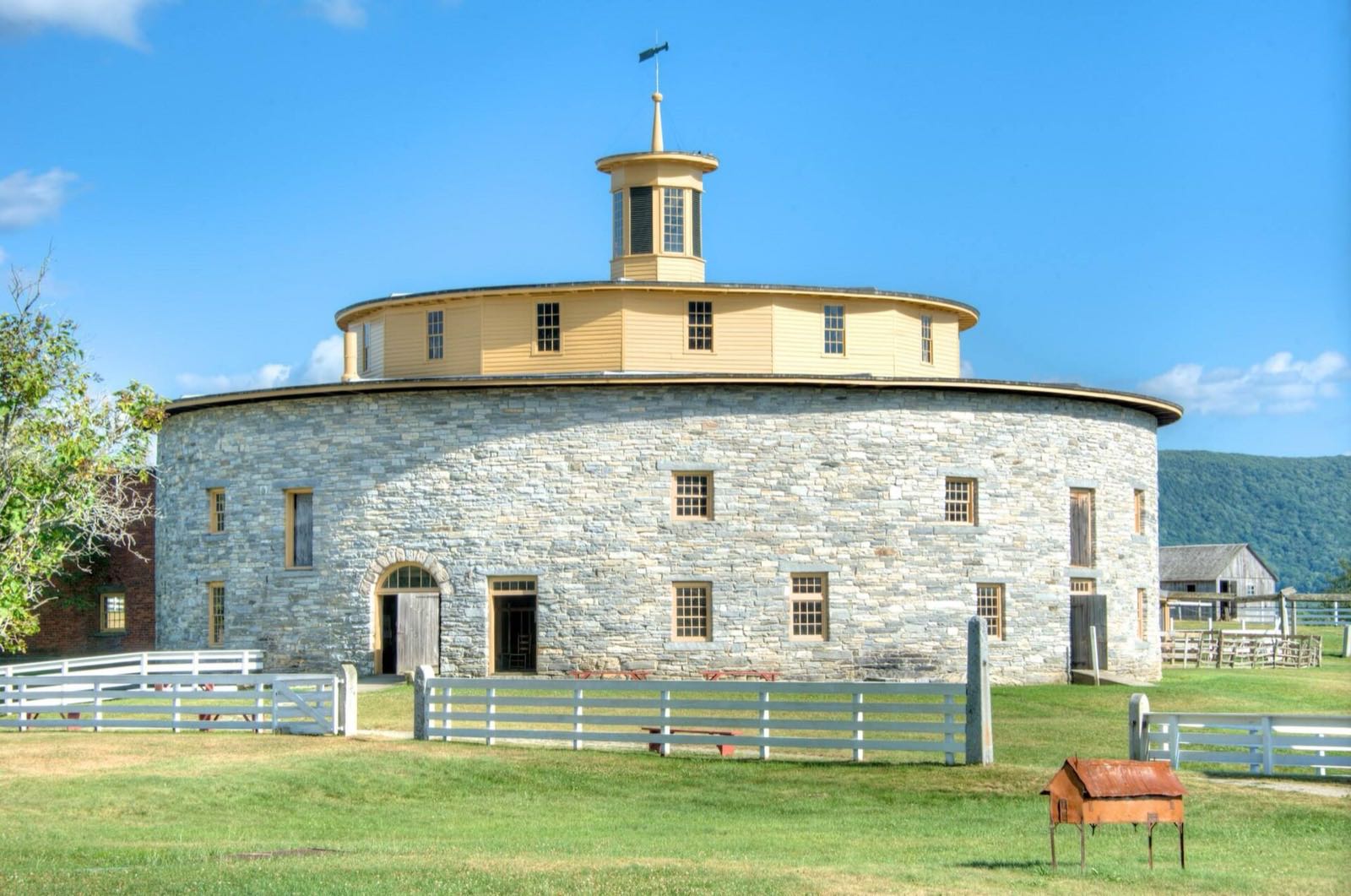 The Round Stone Barn at Hancock Shaker Village, with a Shaker dwelling house in the foreground.