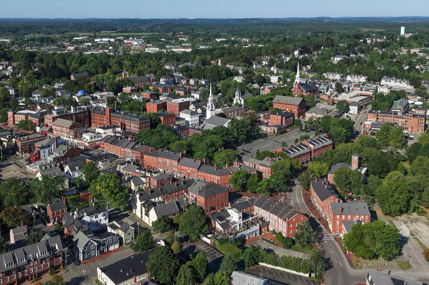 Aerial view of downtown Newburyport's brick buildings and church steeples near the Merrimack River.