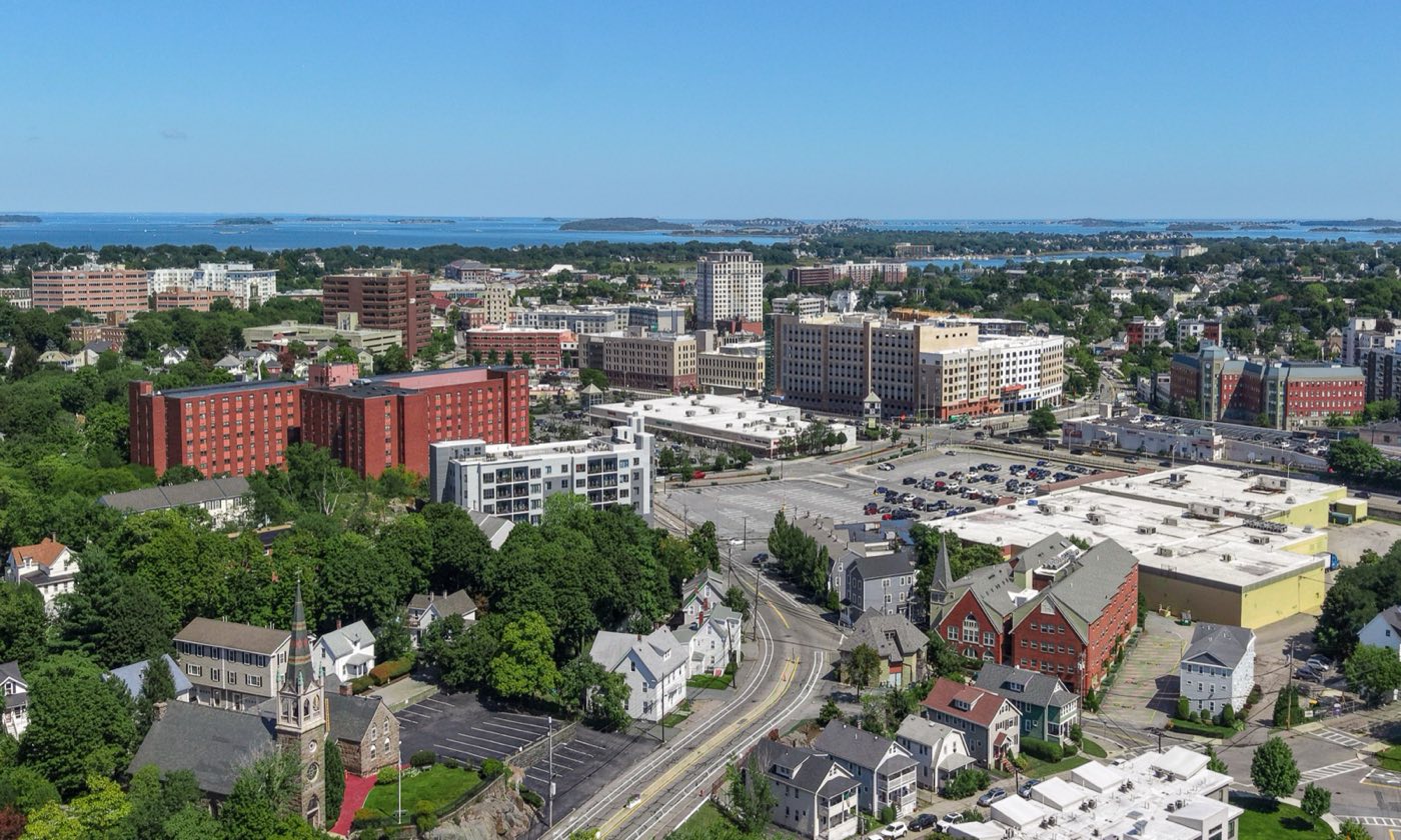 Aerial view of Quincy Center's downtown high-rises with Boston Harbor and its islands in the background.