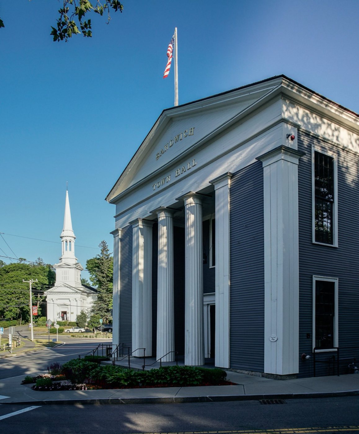 Sandwich Town Hall, a white columned building, with the First Church of Christ steeple behind it.