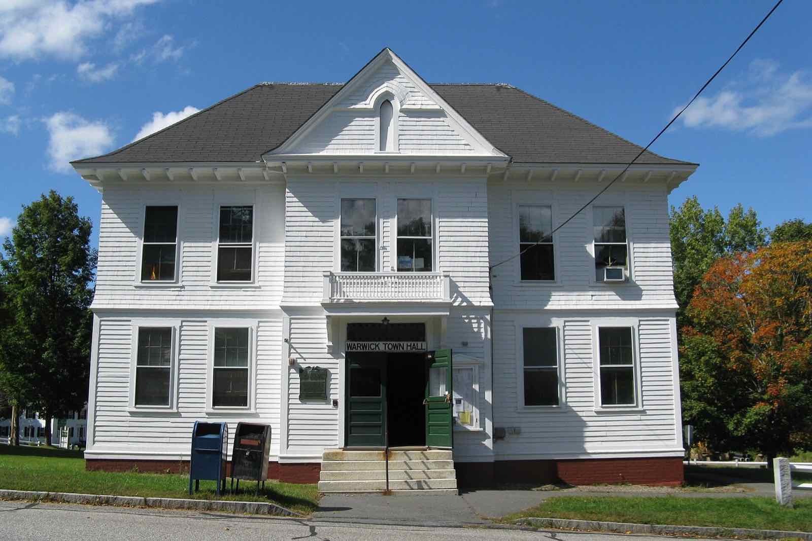 Warwick Town Hall, a white clapboard building with a granite front-step entrance, on Athol Road in Warwick center.