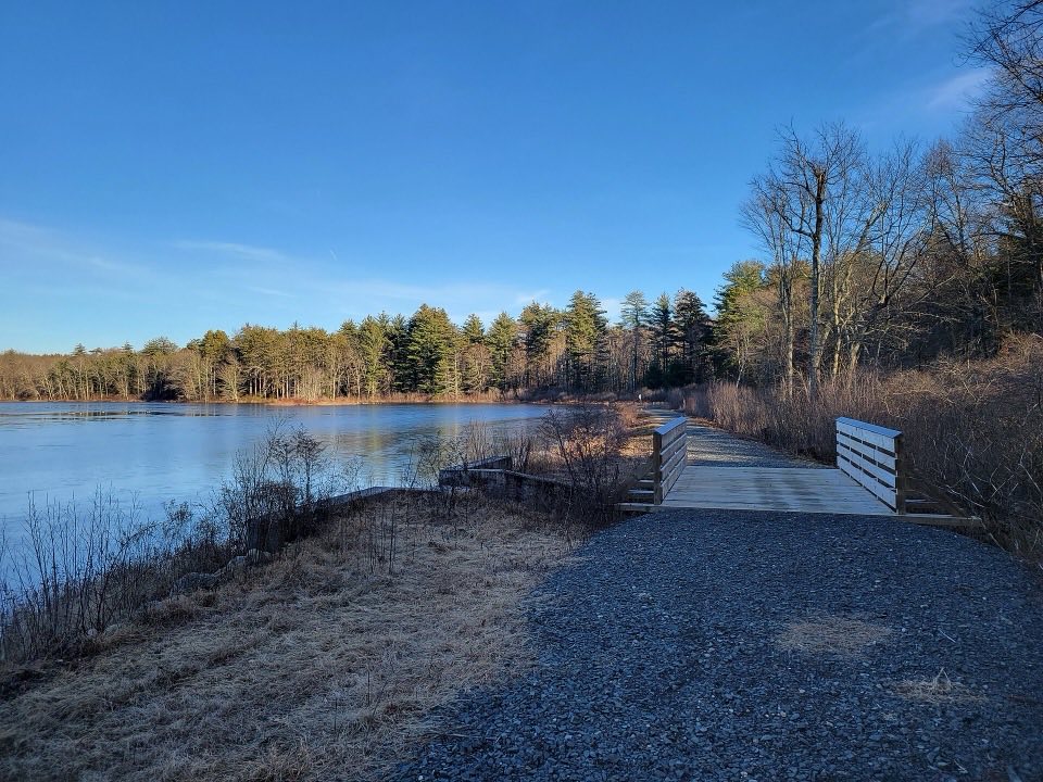 Great Pond in Massacoe State Forest on a clear winter afternoon, with a footbridge along the shore